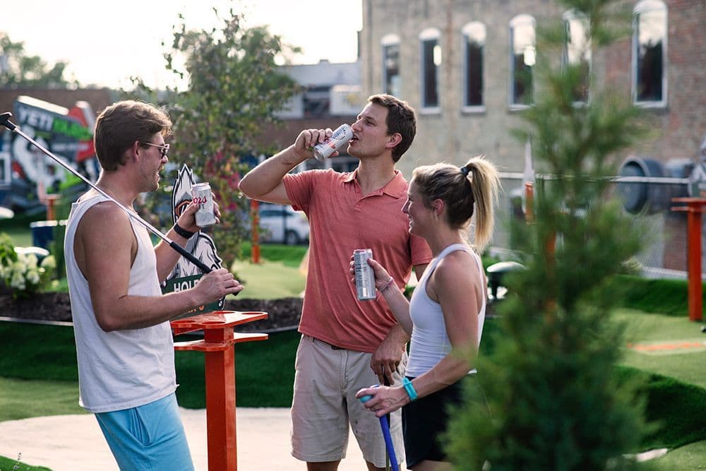 Friends socializing with drinks on the YetiYard mini golf course